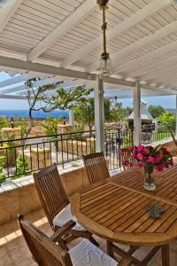 una mesa de madera y sillas en un patio con vistas al océano en Villa Ntora, en Afiartis