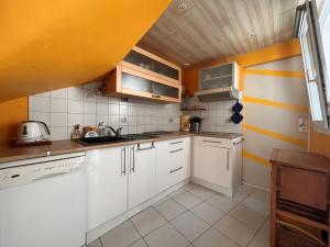 a kitchen with white cabinets and orange walls at Maison avec cour, à 25m de la plage, proche centre et commerces - FR-1-197-573 in Les Sables-dʼOlonne