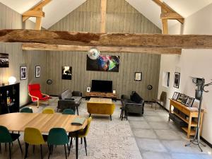 uma sala de estar com mesa e cadeiras em Le Grenier d'Ouilly au cœur du Pays d'Auge - Gîte avec piscine à 20 min des plages em Ouilly-le-Vicomte