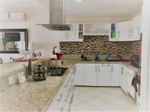 a kitchen with white cabinets and a brick wall at Margate Gardens Opposite beautiful Beach, Bars, Restaurants, Boardwalk, Mall in Bridgetown