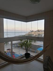 a hammock in a room with a view of the ocean at Apartamento, ampla sacada com vista para o mar! in Itanhaém