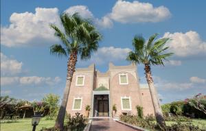 two palm trees in front of a building at Maria Towers , Palais Table d'hôtes & SPA in Marrakesh