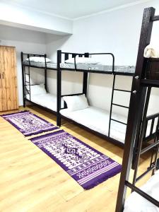 a room with three bunk beds and a rug at Like Home Hostel na Timiryazeva in Almaty