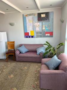 een woonkamer met 2 paarse banken in een kamer bij Peaceful Perch in Walvis Bay