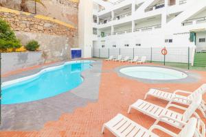 ein Swimmingpool mit Liegestühlen neben einem Gebäude in der Unterkunft Flatguest Namibia SIN ASCENSOR in Mogán