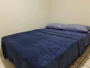 Bett mit blauer Decke in einem Zimmer in der Unterkunft APARTAMENTO EM CONDOMÍNIO FECHADO a 300 METROS DA FABRICA DE CHOCOLATE e a 600 METROS DO RELÓGIO DAS FLORES in Garanhuns
