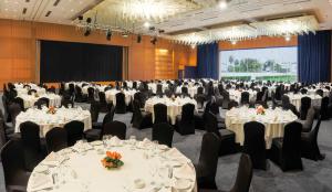 une salle de banquet avec des tables, des chaises et un écran dans l'établissement L' Amphitrite Palace Resort & Spa, à Skhirat