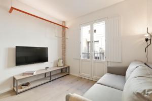 a white living room with a couch and a tv at Bcn Town Apartments Born in Barcelona