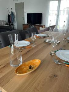 Una mesa de madera con copas de vino y platos encima. en Maison Moderne à Saint-Denis, en Saint-Denis-dʼOléron 19 fotos más