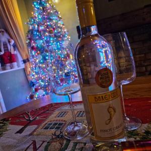 a bottle of wine and a glass next to a christmas tree at Beresford Cottage in Skegness