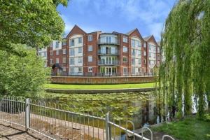 a building with a pond in front of a building at Stafford 2 Bedroom Apartment in Prime Location with Secure Parking in Stafford