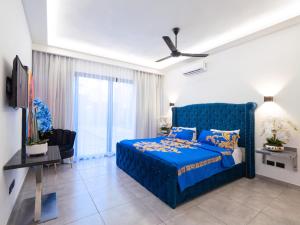 1 dormitorio con 1 cama azul y TV en Instyle Residences at RIZZ SUITES en Sosúa
