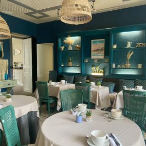 ポルニシェにあるHotel de Charme Le Sud Bretagneの白いテーブルと椅子、青い壁のレストラン