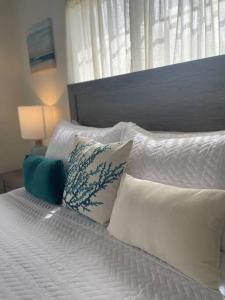 a bed with white pillows on it with a window at Unwind at Idyllic Escape! in Dickenson Bay