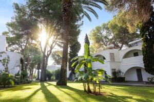 une grande maison blanche avec des palmiers dans la cour dans l'établissement TUI MAGIC LIFE Cala Pada - All Inclusive, à Santa Eulària des Riu