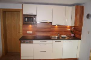 kuchnia z białymi szafkami, zlewem i kuchenką mikrofalową w obiekcie Appartement Spiss w mieście Ried im Oberinntal