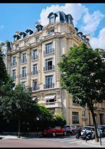 un grand bâtiment avec des voitures garées devant lui dans l'établissement Suite64 - Jacuzzi privatif, à Neuilly-sur-Seine