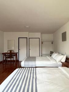 a bedroom with two beds and a table at Nautical Home B&B Khaolak in Khao Lak