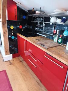 a kitchen with red cabinets and a counter top at The Music Room - Kingsize Double Oak Studio - Sleeps 2 - Quirky - Rural in Haslemere