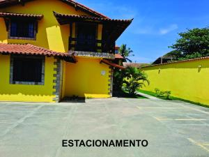 a yellow house with a parking lot in front of it at Uma PAUSA na sua vida, com: sol, praia e sossego! in Cabo Frio