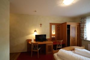 a bedroom with a bed and a desk with a television at Hotel-Gasthof Hirschen in Blumberg
