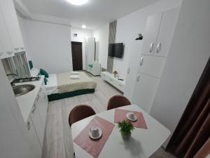 a small white room with a table and a kitchen at Anne Studio in Onești