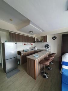 a kitchen with a refrigerator and a counter with bar stools at Amaia Steps Capitol Central N814 in Bacolod