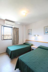 a hotel room with two beds and a television at Apartamentos La Caseta - SABESA in Benidorm