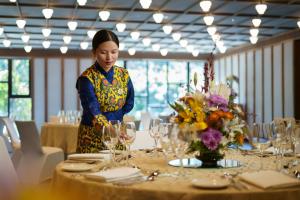 a woman standing in front of a table with wine glasses at Taj Guras Kutir Resort & Spa, Gangtok in Gangtok