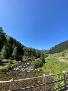 ein Fluss auf einem Feld mit einem Zaun in der Unterkunft APARTAMENTO HEIMA in Incles