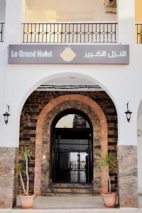 une entrée à un grand hôtel avec deux plantes en pot dans l'établissement LE GRAND HOTEL, à Houmt Souk