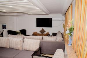 uma sala de estar com um sofá e uma televisão de ecrã plano em LE GRAND HOTEL em Houmt Souk