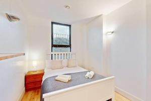 a white bedroom with a bed with two towels at Stunning 2 bed flat with a garden in New Cross in London