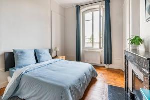 Schlafzimmer mit einem Bett mit blauer Bettwäsche und einem Kamin in der Unterkunft Harmonie 3 Chambres - spacieux in Saint-Étienne
