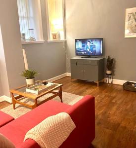 a living room with a couch and a flat screen tv at Ground Floor Flat Close to city in Edinburgh