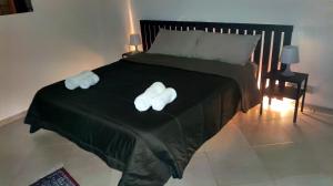 La Casa Di Via Marzulli في أتشيريالي: منشفتان بيضاوان على سرير مع بطانية سوداء