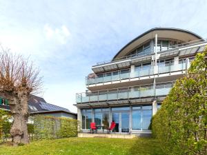 a building with glass windows and two red chairs at Ferienwohnung Panoramablick in Altefähr