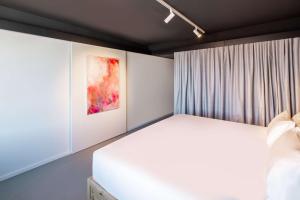 Un dormitorio con una cama blanca y una pintura en nhow Brussels Bloom, en Bruselas