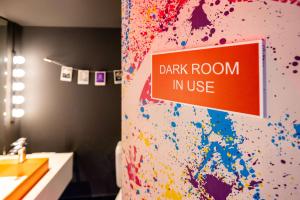 un baño con una habitación oscura con un cartel de uso en la pared en nhow Brussels Bloom, en Bruselas