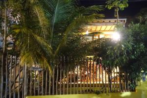 a fence with palm trees in front of a building at Apartamento com jardím e vista por rio, farol e mar in Itacaré