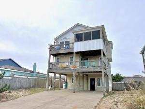 a tall house with a balcony on top of it at The Sandbox in Kill Devil Hills