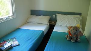 a stuffed elephant sitting between two beds in a room at Happy Camp mobile homes in Camping La Vecchia Torre in Gallipoli