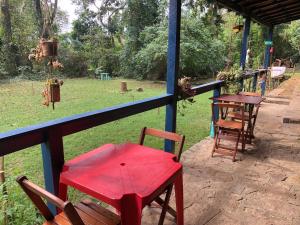 Camping Flamboyant في إلهابيلا: طاولة حمراء وكراسي تجلس على الشرفة