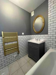 ein Bad mit einem Waschbecken und einem Spiegel in der Unterkunft Appartement Thème Années 20, proche du Puy Du Fou in Pouzauges