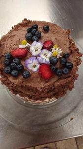 a chocolate cake with strawberries and blueberries and flowers on it at Musik und Theater Gasthof Rössle - Rooms for Angels in Burladingen