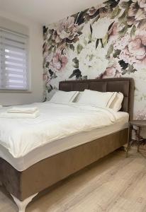 um quarto com uma cama com papel de parede floral em Apartman Enigma em Ruma