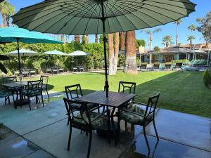 a wooden table with chairs and an umbrella at Vista Grande Resort - A Gay Men's Resort in Palm Springs