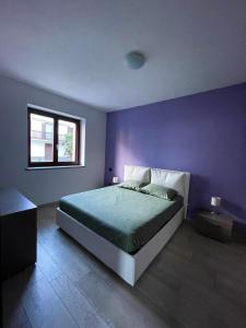 a purple bedroom with a bed and a window at À la Bouteucca in Fenis