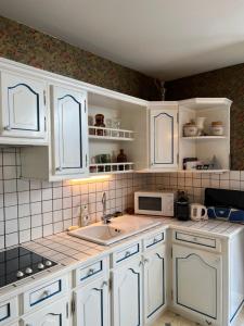 uma cozinha com armários brancos e um lavatório em (A)Typique Chartrons em Bordeaux