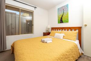 a bedroom with a large yellow bed with towels on it at Hallett Cove House 6Bed 3Bath Full Kitchen Fast Wifi 5TV Netflix Espresso-Perfect for large families in Halletts Cove